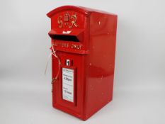 A reproduction, red painted, cast iron fronted postbox with metal shell rear, with two keys,