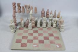 A carved stone chess set and board, 11.