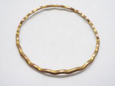 A 9ct gold bangle of undulating form, 7 cm (d), 9.5 grams.