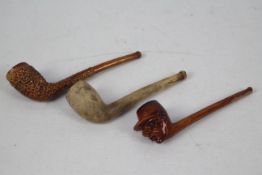 Three clay pipes including Pollocks of Manchester.