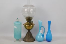 A brass and cast iron oil lamp, 54 cm (h) and three pieces of blue glassware.