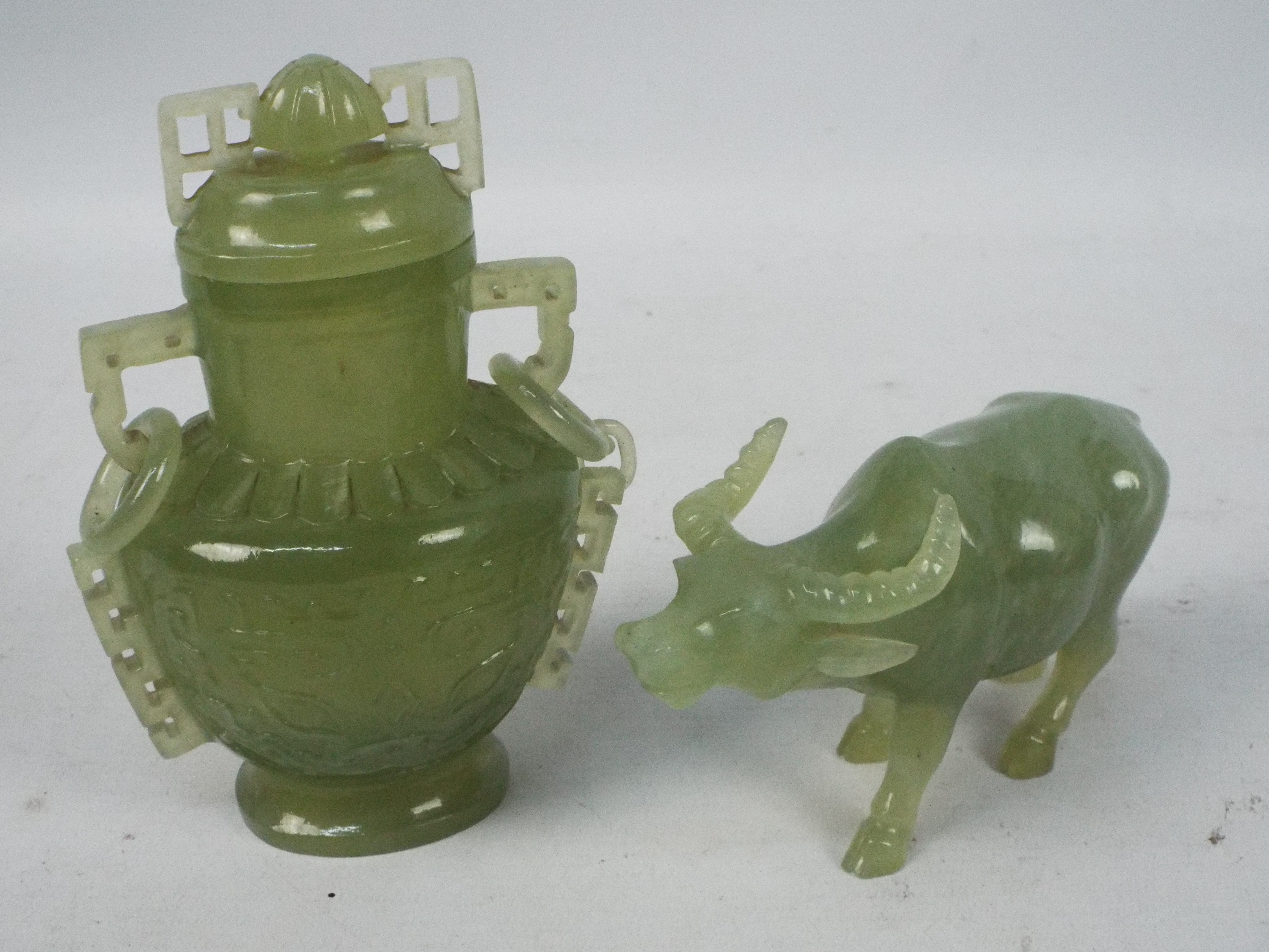 Two Chinese hardstone carvings comprising a vase and cover, 14 cm (h), and a model of a buffalo.