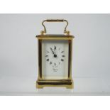 A gilt brass and glass carriage clock, Roman numerals to a white enamel dial marked Rapport London,