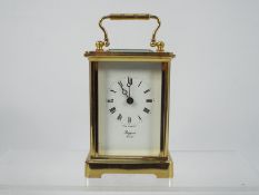 A gilt brass and glass carriage clock, Roman numerals to a white enamel dial marked Rapport London,
