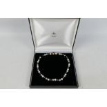 A pearl necklace compromising black, grey and white alternating pearls, each approximately 9 mm,