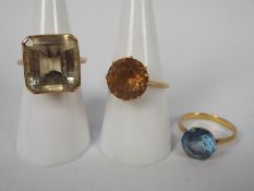 Three lady's yellow metal (presumed 9 ct) dress rings set with a synthetic stones, approx weight 15.