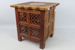 Ethnographica - A square section carved folding table with brass inlay and with enclosed storage ,
