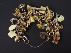 A 9ct rose gold charm bracelet, stamped 9ct, with numerous 9ct charms,