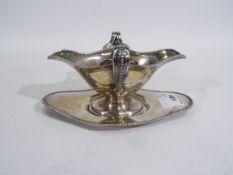 An Edward VII hallmarked silver twin handled sauce boat and stand, Chester assay 1910,