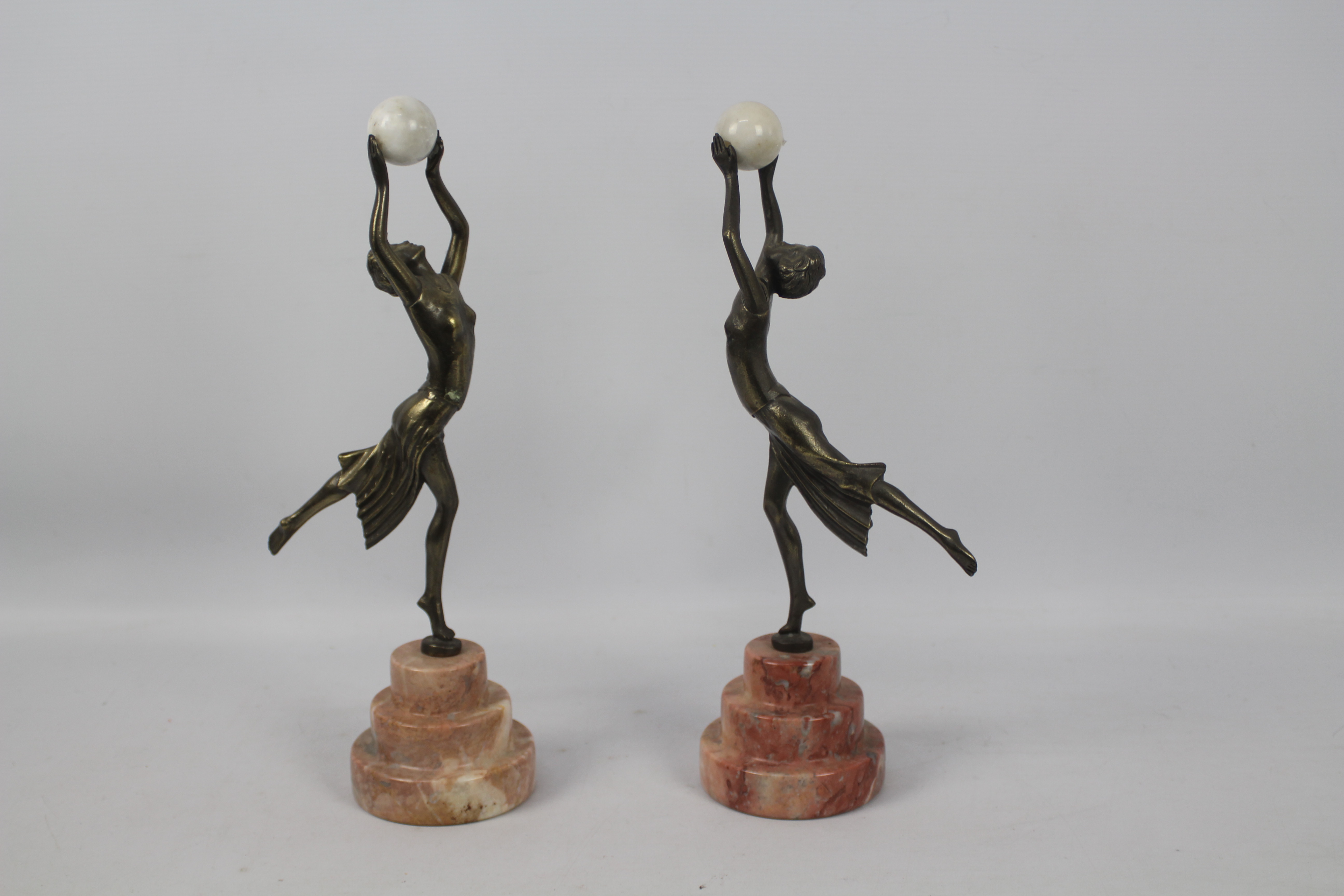 A pair of Art Deco style sculptures modelled as female figures holding aloft spheres,