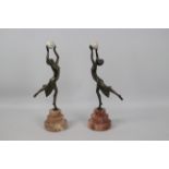 A pair of Art Deco style sculptures modelled as female figures holding aloft spheres,