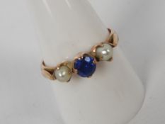 A lady's yellow metal (presumed 9 ct) dress ring set with a synthetic sapphire flanked by pearls,