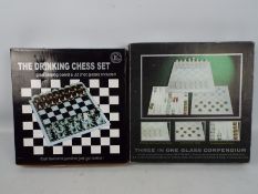 A 3 in 1 glass games compendium and a glass shot glass chess set, both boxed.