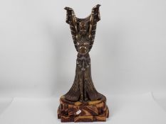 A large Art Deco style figure depicting an Egyptian style female with arms raised,
