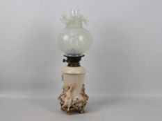 A vintage oil lamp, the base with applied putti amid branches,