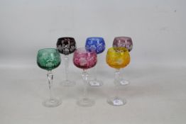 A set of six Harlequin coloured glass to clear hock glasses on faceted stems and spreading feet,