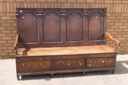 An oak box settle with four panel back, open arms and three drawer box seat,