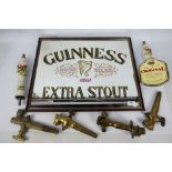 Two ceramic beer pump handles decorated with hunting scenes and a Guinness advertising mirror,