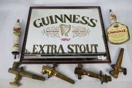 Two ceramic beer pump handles decorated with hunting scenes and a Guinness advertising mirror,