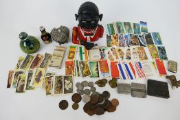 Lot to include a novelty money bank, Mdina paperweight, coins, tea cards, trinket box and similar.