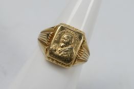 A yellow metal ring stamped 750 for 18ct, bearing image of Pío de Pietrelcina, size M+½,