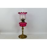 A brass oil lamp with cranberry glass font (font approximately 19 cm diameter) and cranberry tinted