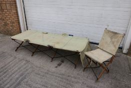 A WWII officers folding campaign bed and chair, of metal and wood construction with canvas supports,