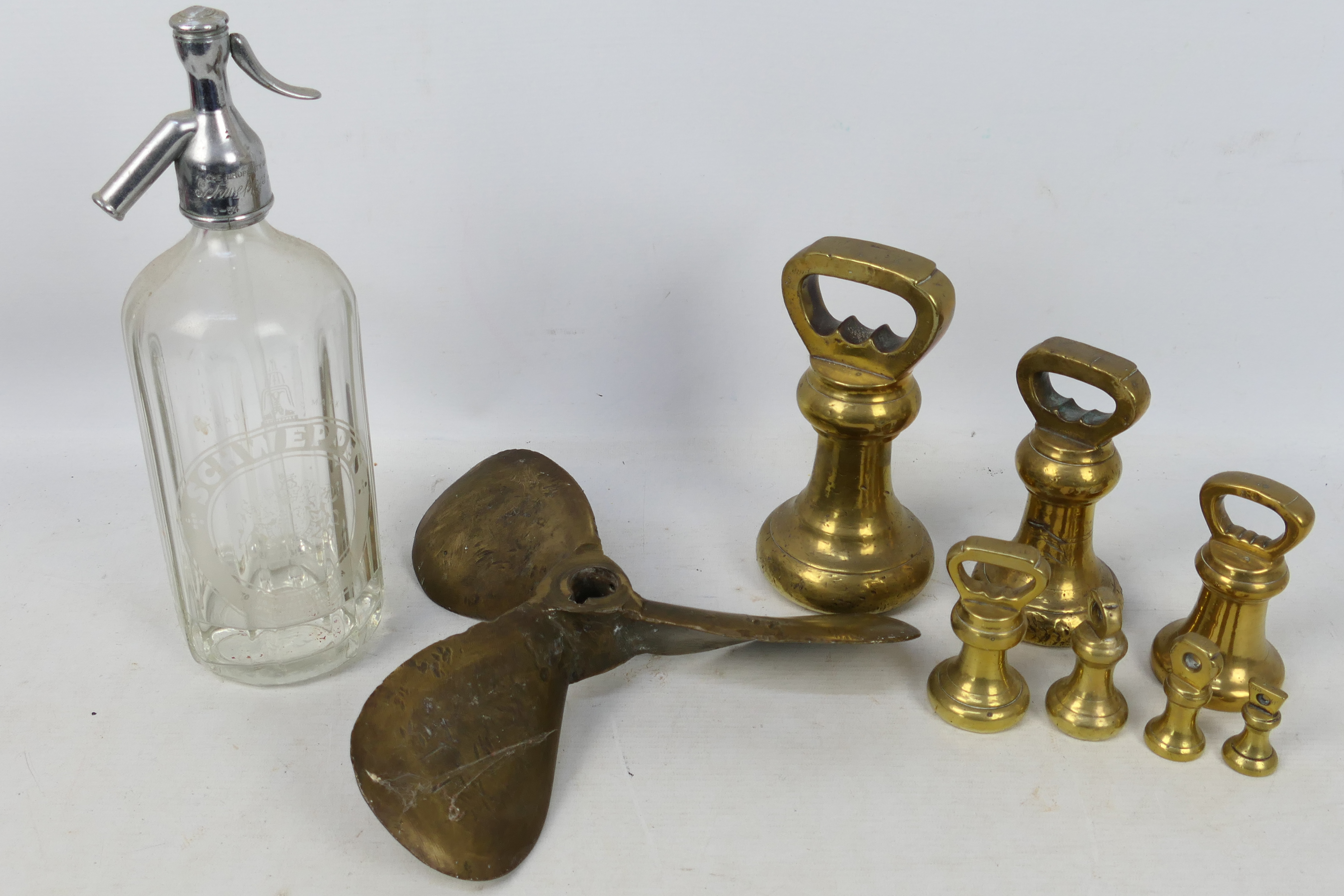 A brass propeller, brass weights and a vintage Schweppes soda syphon.
