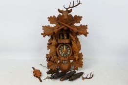 A black forest style cuckoo clock with game carved decoration, with pendulum and weights.