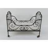 A Napoleon III doll's cot / day bed, iron framed and raised on castors,