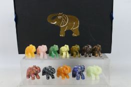 A collection of twelve carved elephants, each carved from a different hardstone,