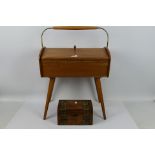 A 1970's teak sewing box raised on tapering supports,