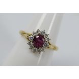 A yellow metal ruby and diamond cluster ring, stamped 0.750 for 18ct, size P, approximately 3.