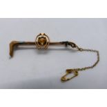 A rose metal bar brooch, stamped 9ct, in the form of a hunting crop with fox mask within horseshoe,