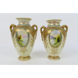 Noritake - A pair of twin handled vases with hand painted landscape scene panels depicting a