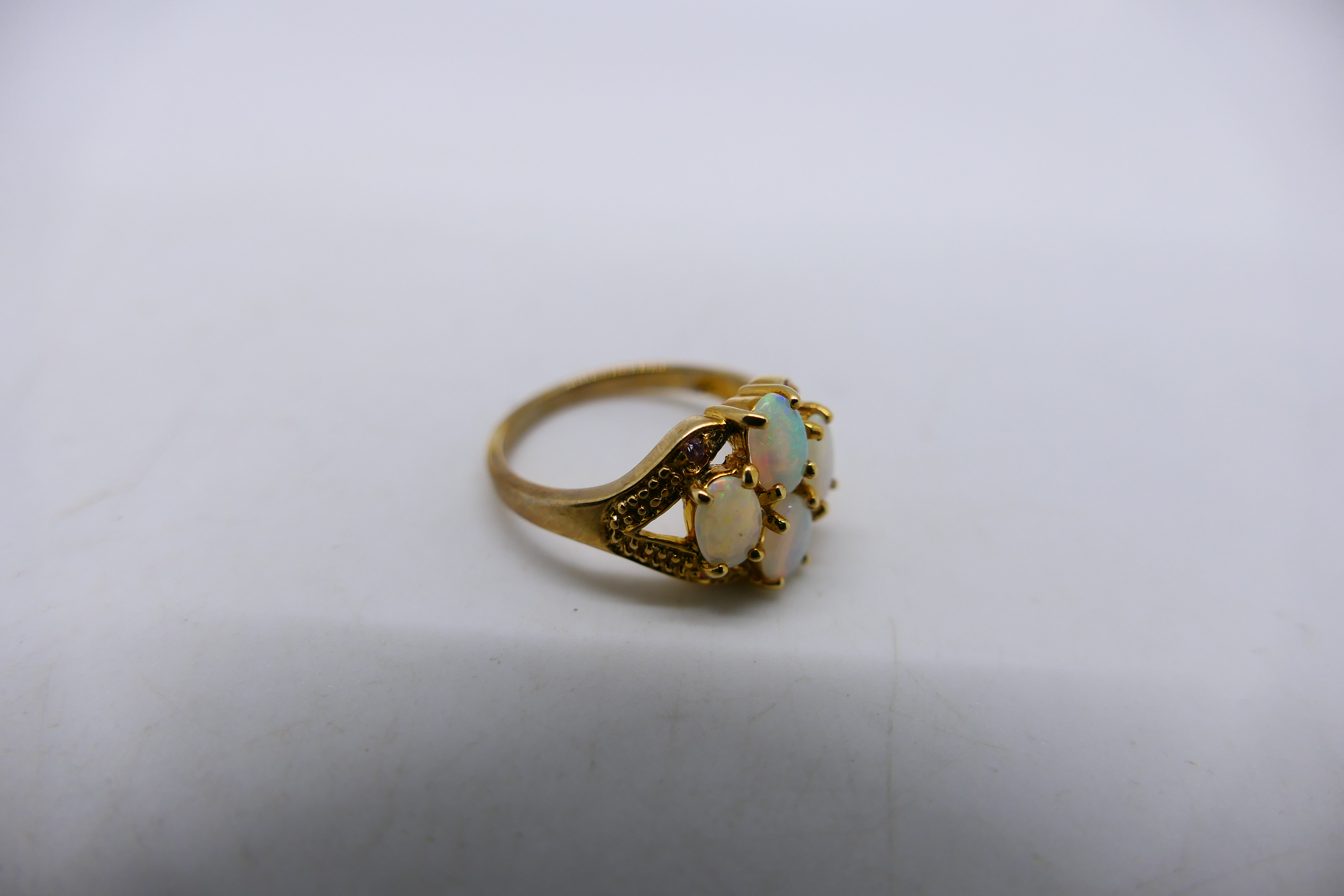 A 9ct yellow gold ring set with four white opal cabochons, size N and a yellow metal, - Image 4 of 5