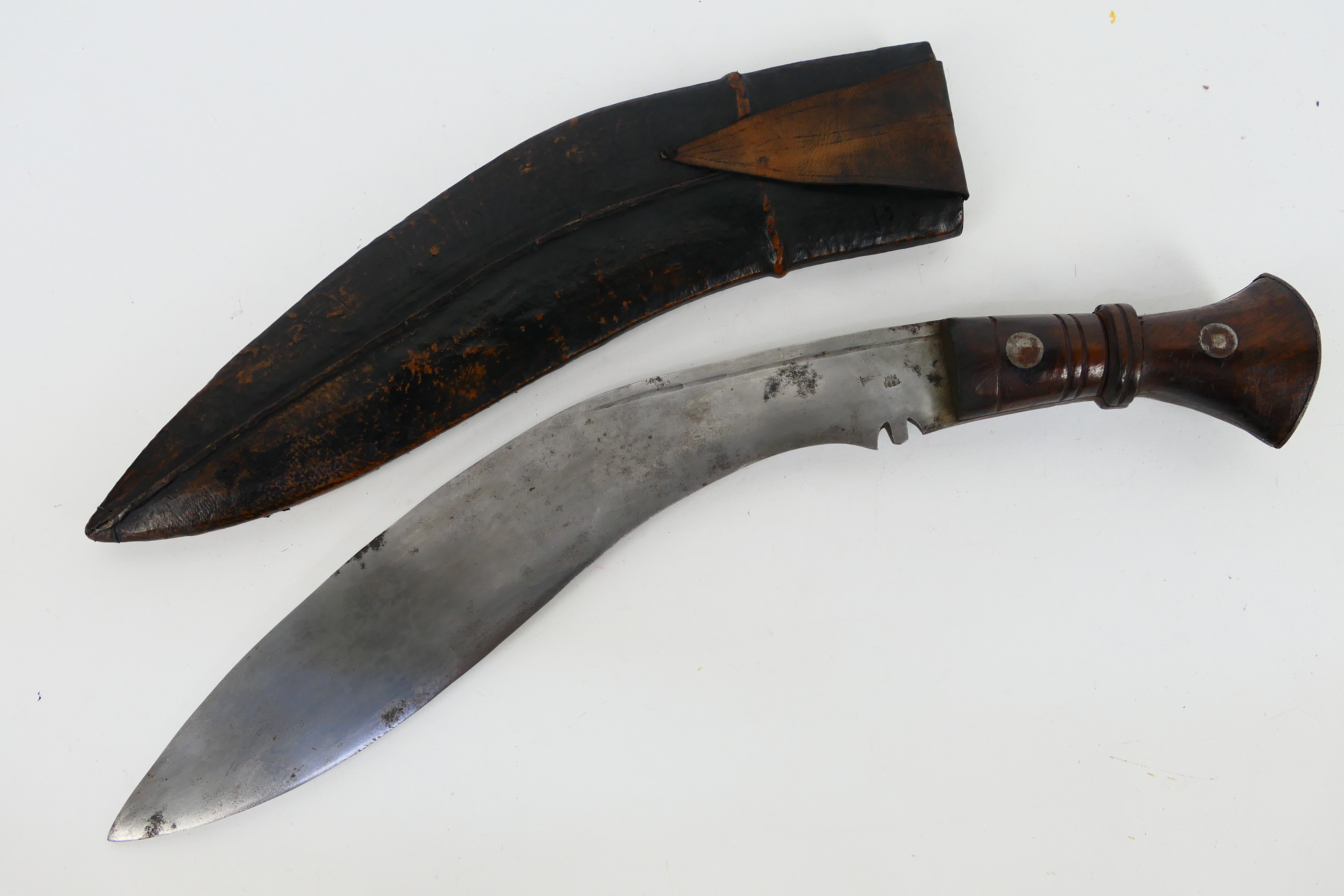 A Gurkha kukri knife, dated 1916, turned wooden hilt with metal pommel, housed in leather sheath.