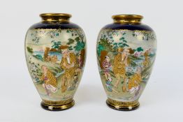 A pair of Japanese Satsuma ware vases decorated with two panels of figures in a garden setting