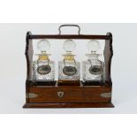 A three decanter tantalus (no apparent makers mark) with decanters and white metal labels.
