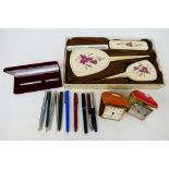 A boxed vintage dressing table set, a quantity of pens including Parker and two travel alarm clocks.