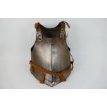 A metal military armour breast plate. 40 cm (h) x 60 cm (l). Appears to be in rusty condition.