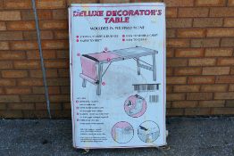 A boxed Deluxe Decorator's Table, approximately 60 cm x 180 cm (60 cm x 90 cm when folded).