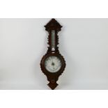 An oak cased aneroid barometer with carved decoration, marked to the dial Eustance & Co Warrington,