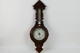 An oak cased aneroid barometer with carved decoration, marked to the dial Eustance & Co Warrington,