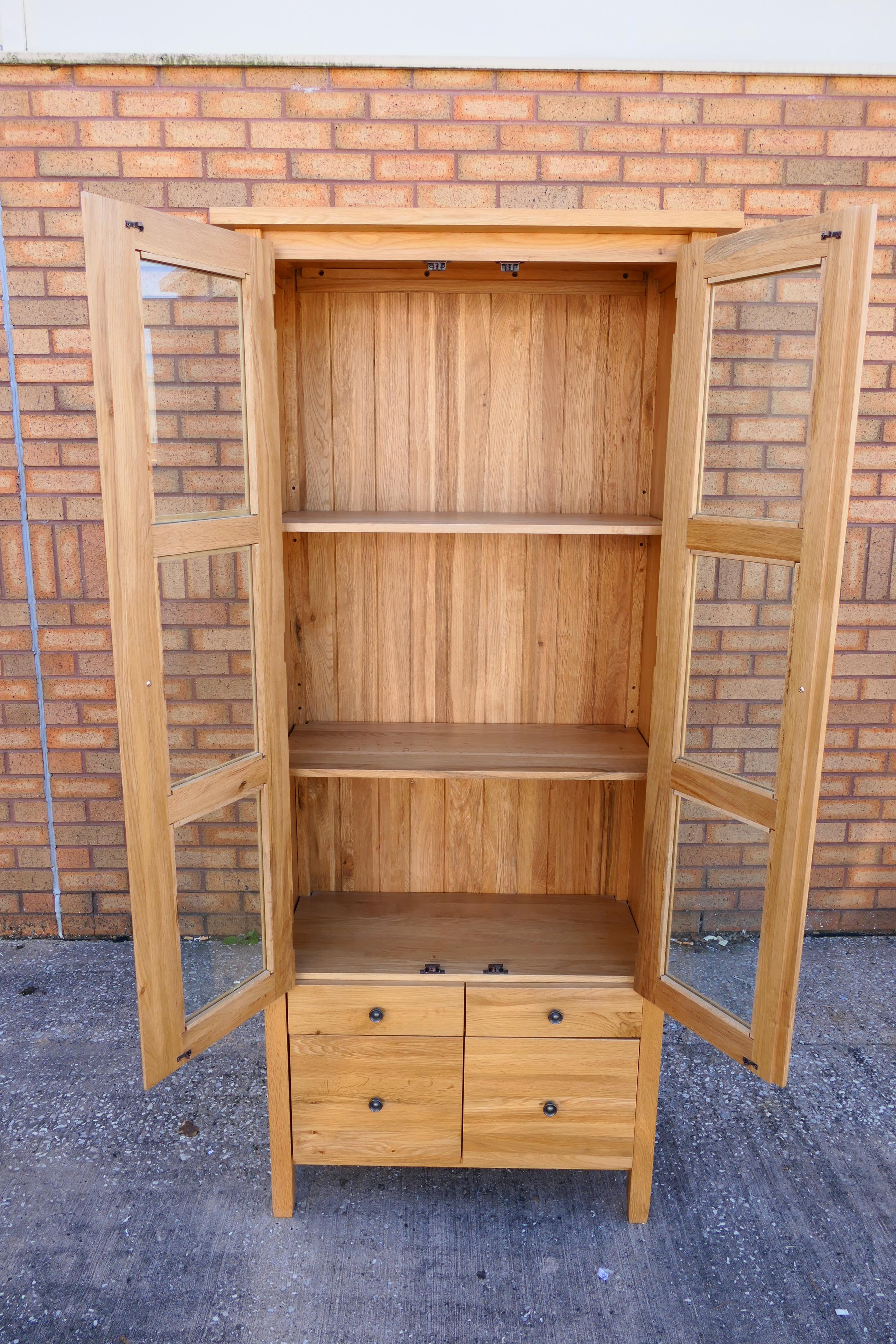 A light oak cabinet with twin glazed doors enclosing two shelves over four short drawers, - Image 3 of 4