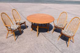 An Ercol drop leaf dining table with four Quaker dining chairs (2+2),