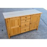 A light oak sideboard with four central, graduated drawers flanked by single door cupboards,