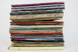 A collection of 12" vinyl records to include Rod Stewart, Simon & Garfunkel, Queen,