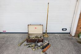 A vintage suitcase containing a quantity of various horse brasses, ships wheel nutcracker,