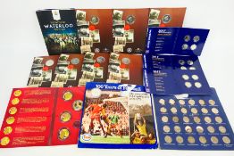 A quantity of commemorative coin collector wallets, each containing the initial coin of issue,